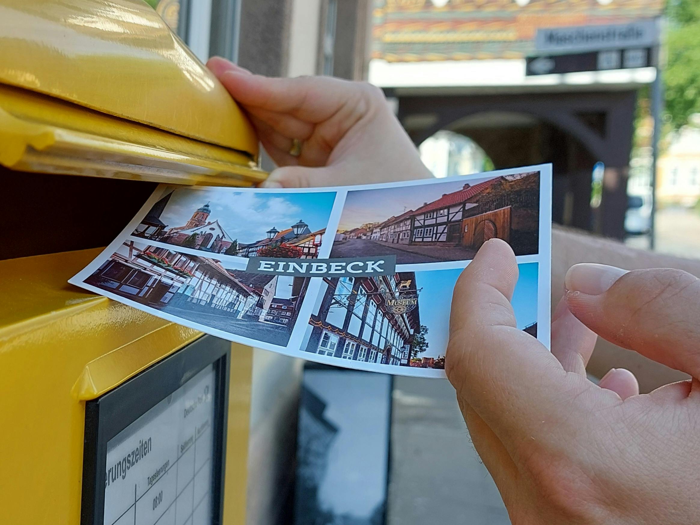 Nahaufnahme Eines Mannes, Der Eine Postkarte In Den Briefkasten Wirft